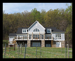 New residence designed by Candace Smith Architect with stone foundation and pergola at rear deck, located near vineyard in Nelson County, Virginia
