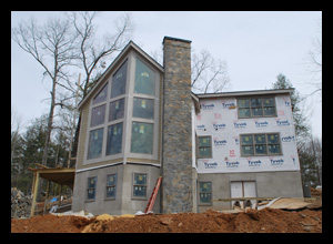 Contemporary new residence under construction in Albemarle County, Virginia, with large glass windows angled for view of river and mountains beyond, designed by Candace Smith Architect