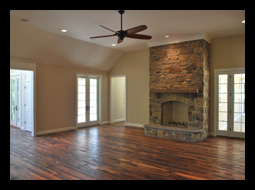 New great room with stone fireplace and antique flooring and screened porch beyond for residence in Charlottesville, Virginia, designed Candace M.P. Smith Architect