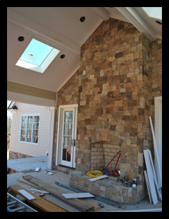 New residence under construction in Albemarle County, Virginia, with covered porch with fieldstone fireplace and walls, and skylights and beadboard ceiling designed by Candace Smith Architect